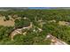 Scenic aerial view capturing a house with solar panels and a pool, surrounded by lush trees and a distant lake at 18695 Ne 5Th Terrace Rd, Citra, FL 32113
