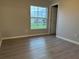 Bedroom with wood-look floors, neutral walls, base molding, and a window at 203 Locust Pass, Ocala, FL 34472