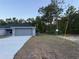 View of the home's exterior with a two-car garage, fresh lawn and tall trees in the background at 227 Locust Rd, Ocala, FL 34472