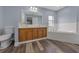 Well-lit main bathroom with double vanity, large mirror, and separate tub at 2312 Sw 140Th Ct, Ocala, FL 34481