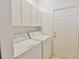 Bright laundry room with washer, dryer, and storage cabinets near the exit door at 2339 Nw 55Th Avenue Rd, Ocala, FL 34482