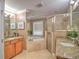 Bright bathroom featuring a soaking tub, granite countertop vanity, and glass-enclosed shower at 2410 Se 23Rd Pl, Ocala, FL 34471