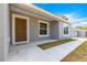 Inviting covered front porch featuring a stylish wood front door, modern paint, and freshly poured concrete at 37 Fisher Lane Way, Ocklawaha, FL 32179