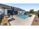 Backyard showcasing a pool with patio, grill, and a blue umbrella in a fenced yard with views of surrounding homes at 4083 Se 38Th Loop, Ocala, FL 34480