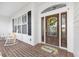 Cozy front porch with brick flooring, rocking chairs, a decorative wreath, and a welcoming 
