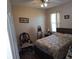 This bedroom features a patterned bedspread, chair, and window with blinds at 4770 Sw 114Th St, Ocala, FL 34476