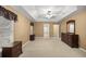 Primary bedroom with a tray ceiling, neutral carpet, dresser, and a glimpse of the bathroom at 4939 Sw 99Th Pl, Ocala, FL 34476