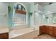 Bathroom featuring tile floors, a garden tub, wooden cabinetry and ample lighting at 6045 Ne 65Th St, Silver Springs, FL 34488