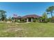Sprawling single-story home featuring a manicured lawn, mature trees, and American flag at 6045 Ne 65Th St, Silver Springs, FL 34488