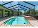 The sparkling pool has clear blue water, and is surrounded by brick pavers and a screened-in enclosure at 6045 Ne 65Th St, Silver Springs, FL 34488