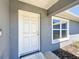 Inviting front entrance featuring a white door, gray exterior, and a window allowing natural light to filter in at 6671 Se 108Th St, Belleview, FL 34420