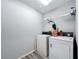Bright laundry room featuring a white washer and dryer set, shelving for storage, and modern gray walls at 6671 Se 108Th St, Belleview, FL 34420