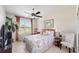 Well-lit bedroom featuring a ceiling fan, cozy furniture, and a large window overlooking a green exterior at 7503 Sw 97Th Terrace Rd, Ocala, FL 34481