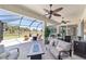 Outdoor living space with a screened patio, multiple seating areas, ceiling fans, and views of the surrounding landscape at 7503 Sw 97Th Terrace Rd, Ocala, FL 34481