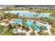 Aerial view of a resort-style pool area with palm trees, lounge chairs, and a scenic lake backdrop at 7503 Sw 97Th Terrace Rd, Ocala, FL 34481