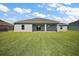 Large backyard featuring a lush green lawn and the back of the house, with sliding glass doors at 8725 Sw 136Th Ter, Dunnellon, FL 34432