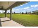 Expansive backyard view from the covered patio, showing a well-manicured lawn and distant trees at 8725 Sw 136Th Ter, Dunnellon, FL 34432