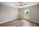 Cozy bedroom featuring a ceiling fan, wood-look flooring, and a window providing ample natural light and outdoor views at 8725 Sw 136Th Ter, Dunnellon, FL 34432