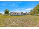Wide shot of home's backyard featuring green grass, blue skies, and mature trees in a partially fenced yard at 10946 Sw 65Th Ave, Ocala, FL 34476