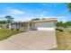 Home featuring a large driveway leading to an attached two-car garage and a screened-in porch at 10946 Sw 65Th Ave, Ocala, FL 34476
