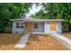 Exterior view of a single-story home with a gray exterior, boarded windows, and landscaping needs some attention at 1325 42Nd St, Orlando, FL 32839