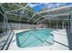 The screened-in pool is surrounded by a white concrete pool deck with a fence and trees in the background at 14476 Sw 43Rd Court Rd, Ocala, FL 34473