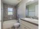 Bathroom features a shower-tub combination, gray tile walls and flooring, and a single sink vanity at 1453 Ne 161St Pl, Citra, FL 32113