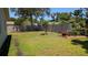 Landscaped backyard featuring a well-maintained lawn, mature trees, and a charming patio area at 2219 Ne 18 Ave, Ocala, FL 34470