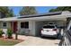 Charming single-story home featuring solar panels, a red front door, and cozy carport at 2219 Ne 18 Ave, Ocala, FL 34470