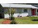 Landscaped front yard with a charming red door and freshly painted light gray exterior at 2219 Ne 18 Ave, Ocala, FL 34470
