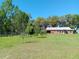 View of the single-story home with an entrance porch, a metal roof and several windows set amongst lush greenery at 2630 Nw 140Th St, Citra, FL 32113