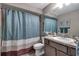 Well-lit bathroom with a granite vanity, tiled shower, and a blue shower curtain, creating a calm atmosphere at 5090 Nw 80Th Avenue Rd, Ocala, FL 34482