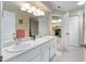 Bright bathroom featuring double sinks, white cabinetry, and access to the kitchen and a shower at 8237 108Th Street Sw Rd, Ocala, FL 34481