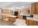 Eat-in kitchen features central island, light countertops and light wood cabinetry, and black appliances at 8831 Sw 94Th Ln # H, Ocala, FL 34481
