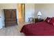 Comfortable bedroom with red bedding, wood floors, and a decorative cabinet leading to the bathroom at 9288 Sw 93Rd Cir, Ocala, FL 34481