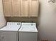 Laundry room with a washer and dryer under warm wood-tone cabinets at 9288 Sw 93Rd Cir, Ocala, FL 34481