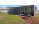 The backyard features a screened in patio, a grassy lawn, and fresh mulch landscaping at 9764 Sw 81St Ln, Ocala, FL 34481