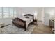 Cozy bedroom featuring wood-style floors, a decorative rug, a carved bed frame, and plantation shutters at 9764 Sw 81St Ln, Ocala, FL 34481