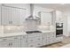 Bright kitchen showcases white cabinetry, stone countertops, subway tile backsplash, stainless steel range hood, and built-in oven at 9764 Sw 81St Ln, Ocala, FL 34481