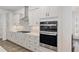 Well-equipped kitchen featuring white cabinets, subway tile backsplash, stone countertops, a stainless steel range hood, and built-in oven at 9764 Sw 81St Ln, Ocala, FL 34481