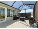 Inviting screened-in patio with wicker seating, fire pit table, and sliding glass doors to the interior at 9764 Sw 81St Ln, Ocala, FL 34481