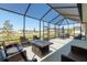 Relaxing screened-in patio with wicker furniture, fire pit table, and view of the landscaped backyard at 9764 Sw 81St Ln, Ocala, FL 34481