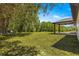 Expansive backyard with mature trees and a covered patio, perfect for outdoor living at 10605 Se 146Th Ln, Summerfield, FL 34491