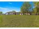 Expansive backyard with lush green grass, mature trees, and a covered patio for relaxing at 10605 Se 146Th Ln, Summerfield, FL 34491