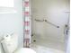 Close-up of the walk-in shower with grab bars and a floral shower curtain at 11536 Sw 138Th Ln, Dunnellon, FL 34432