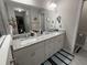 Bathroom featuring a dual sink vanity with granite countertops, a large mirror, and gray tiled floors at 13356 Sw 66Th St, Ocala, FL 34481