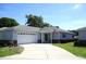 Charming single-story home featuring an attached two-car garage, American flag, and well-manicured lawn at 13675 Sw 111Th Ave, Dunnellon, FL 34432