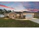 Charming single-story home with a two-car garage, landscaped front yard and colorful sunset at 14085 Sw 34Th Terrace Rd, Ocala, FL 34473
