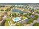 An aerial view shows a large community pool and nearby golf course featuring a tranquil pond surrounded by green landscapes at 2693 Craven Way, The Villages, FL 32162