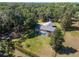An aerial view of a screened pool home on a lush green lawn surrounded by mature trees and a fenced yard at 3230 Se 45Th St, Ocala, FL 34480